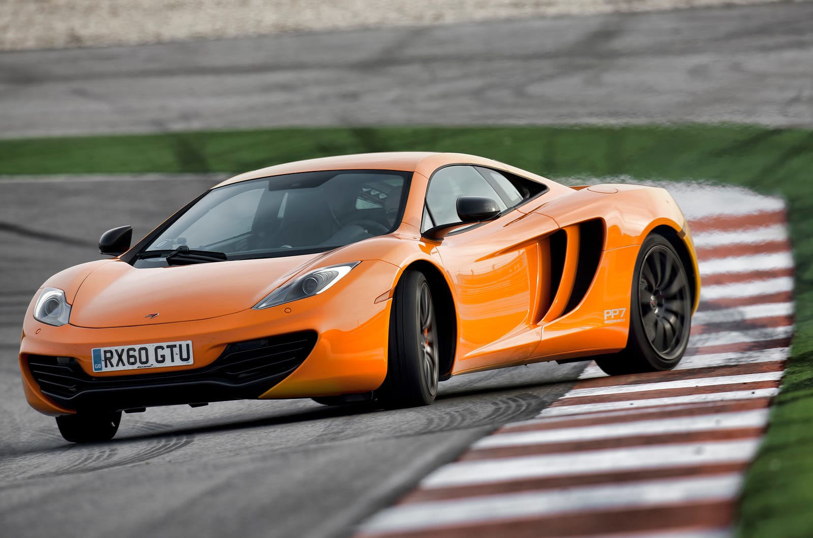 McLaren MP4-12C in orange cornering on a racing circuit