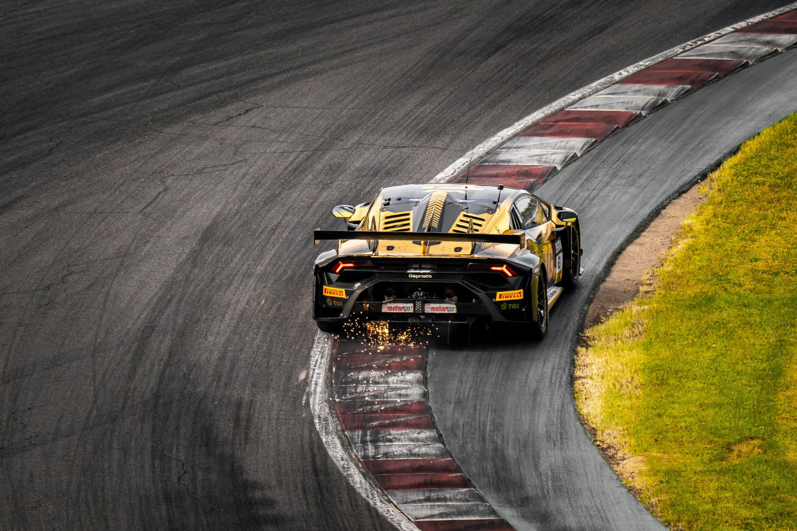 A yellow Lamborghini Huracán GT3 cornering with sparks trailing from the floor