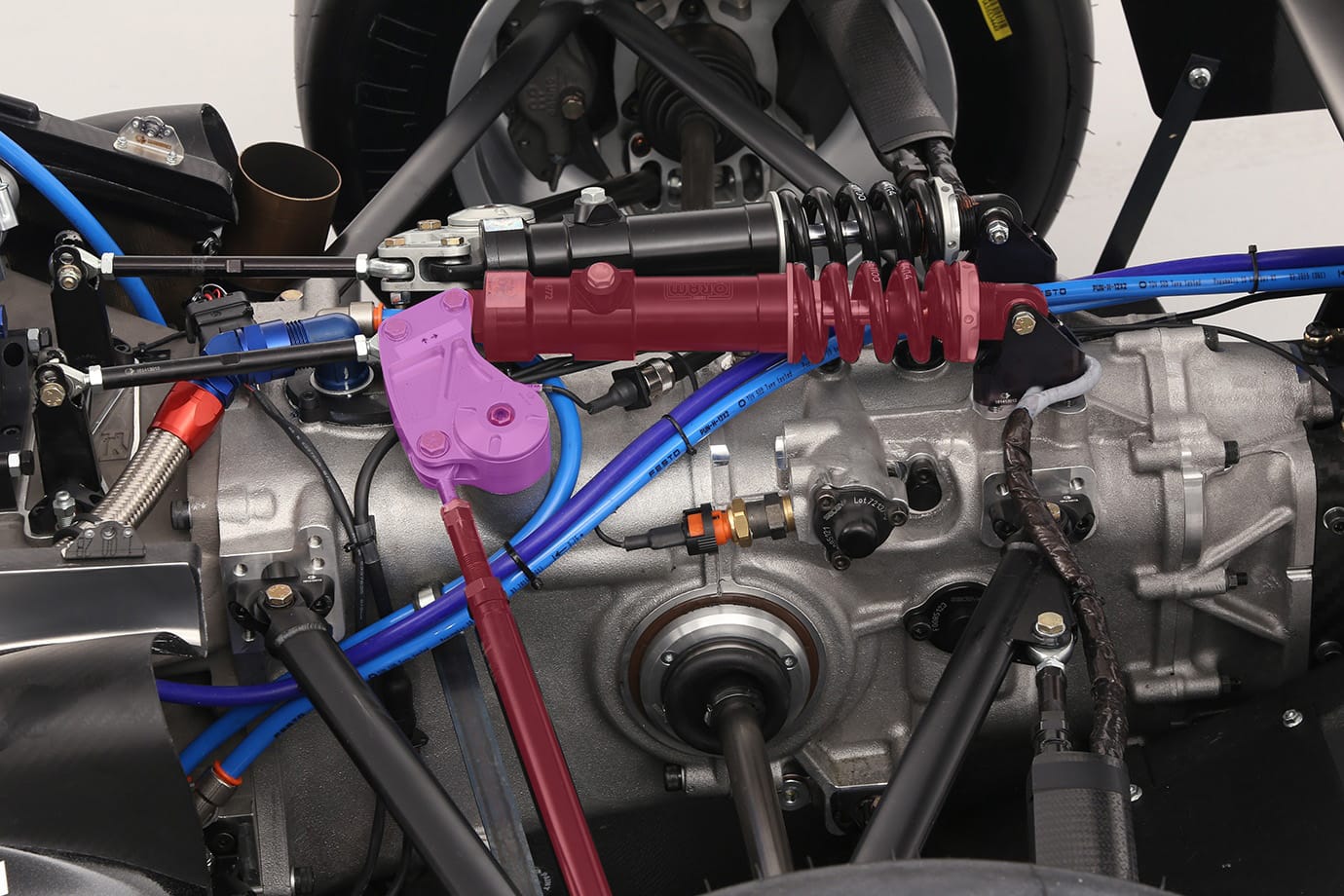 F3 racing car suspension assembly showing pushrod actuation, bell crank highlighted in purple, and inboard spring-damper unit